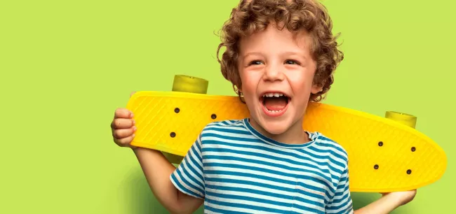 Kind lacht met skatebord op zijn schouders